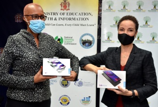 Minister of Education, Youth and Information, Hon. Fayval Williams (left), and Minister of Foreign Affairs and Foreign Trade, Senator the Hon. Kamina Johnson Smith, knock elbows at the handover of  tablet computers donated by persons in the diaspora for students in Jamaica, at the Education Ministry,  in Kingston, today (February 16)