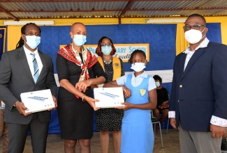 Minister of Education, Youth and Information, Hon. Fayval Williams (second left), hands over a tablet computer to a student of the Gregory Park Primary School, Amoya Venson, during a ceremony held at the school’s Portmore, St. Catherine, location on Wednesday (February 24). Also pictured (from left) are State Minister in the Ministry of Culture, Gender, Entertainment and Sport, and Member of Parliament for East Central St. Catherine, Hon. Alando Terrelonge;  Past Presidents' Council Chair, Kiwanis Club of South St. Catherine, Dione Chambers; and Principal of the school, Richard Williams. During the ceremony, 26 tablet computers were handed over to the school by the Kiwanis Club of South St. Catherine.

