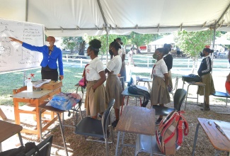 Minister of Education, Youth & Information, Hon. Fayval Williams (left, at board), interacts with Mona High School students in their outdoor classroom, during a tour of the institution on February 4.