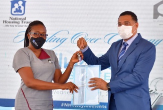 Prime Minister, the Most Hon. Andrew Holness (right), presents new homeowner, Treveen Palmer, with her keys to a unit in the National Housing Trust’s (NHT) SilverSun Estate development in St. Catherine, recently.

