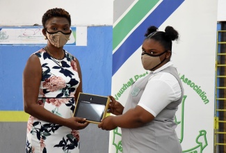 Vice Principal and past student of Vauxhall High School, Annette Campbell Burke (left), presents grade-eight student, Yolanda Forbes, with a tablet. Occasion was the handover of  61 tablets, donated by the Vauxhall High School Alumni Association, Jamaican Diaspora. The event was held at the institution’s Windward Road address, in East Kingston, recently.

