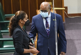 Minster of Tourism, Hon Edmund Bartlett, CD., MP., speaks with Lisa Hanna, MP., Member of Parliament for St Ann South Eastern at sitting of Parliament today, Tuesday April 20.