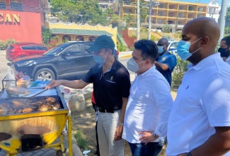 Minister without Portfolio in the Ministry of National Security, Senator the Hon. Matthew Samuda (centre) and Councillor for the Spring Garden Division in St. James, Dwight Crawford (right), observe as Minister of National Security, Hon. Dr. Horace Chang (left), tends to a pan of jerk chicken  along Jimmy Cliff Boulevard in Montego Bay, St. James, on April 5. Occasion was a meeting with business entities participating in the E-commerce National Delivery Solution (ENDS) programme, which commenced in the Second City on April 2.

