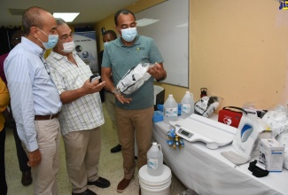 Health and Wellness Minister, Dr. the Hon. Christopher Tufton (right), looks on as Custos of Clarendon, William Shagoury (centre), points out features of some of the supplies donated to the May Pen and Lionel Town hospitals. At left is Chairman of the Southern Regional Health Authority, Wayne Chen.  The items, valued at some $12 million, were handed over by Custos Shagoury, during a ceremony on Friday (June 18) at the May Pen Hospital.