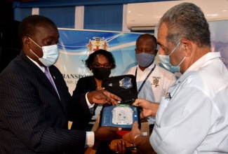 Minister of Transport and Mining, Hon. Robert Montague (left), and Chairman of the Airports Authority of Jamaica (AAJ), Hon. William “Billy” Shagoury (right), display a defibrillator, donated to the May Pen Hospital, in Clarendon, by Mr. Shagoury, at a presentation ceremony held at the Ministry in St. Andrew on Tuesday (June 22). Also sharing in the occasion (from second left) are Chief Executive Officer of the Hospital, Eugenia Clarke-James and

Senior Medical Officer at the hospital, Dr. Bradley Edwards.