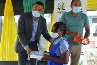 Prime Minister, the Most Hon. Andrew Holness (left), presents student at the St. Catherine-based Kitson Town Primary School, Annique Campbell, with a tablet computer, in Pedro, on Friday (June 18). Sharing in the occasion is Member of Parliament for St. Catherine West Central, Dr. the Hon. Christopher Tufton. The Prime Minister donated tablets to 30 students in the parish, from his Positive Jamaica Foundation.

