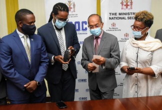 Minister of National Security, Hon. Dr. Horace Chang (second right), inspects a traffic ticket that was printed from one of the smart android devices and portable printer that will be carried by traffic police in the Corporate Area to facilitate the electronic issuance of traffic tickets, among other things. Also sharing in the moment (from left) are Deputy Commissioner of Police in charge of the Public Safety and Traffic Enforcement Branch, Dr. Kevin Blake; Senior Director, Technology Transformation in the Ministry, Arvel Grant; and former Permanent Secretary in the Ministry, Dianne McIntosh. Occasion was the official launch of the handheld ticketing pilot programme, at the Ministry’s Oxford Road offices, in St. Andrew. 