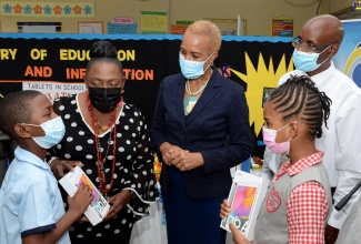 Member of Parliament for St. Catherine Central and Minister of Culture, Gender, Entertainment and Sport, Hon. Olivia Grange (2nd left) and Education, Youth and Information Minister, Hon. Fayval Williams (centre) listen attentively to grade six student at the Eltham Park Primary School,  Zuriel Radcliffe (left), at a handover ceremony for tablet computers held on July 9, at the school in St. Catherine. Others from (2nd right ) are Guidance Counsellor, Ensom City Primary, Ian Ashley and Grade four student at the Ensom City Primary school, Chevanese Williams.