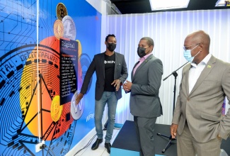 Minister of Agriculture and Fisheries,  Hon. Floyd Green (centre), discussing digital currency evolution with the online payment facilitator WiPay’s Country Manager for Jamaica, Kibwe McGann (left) and Chairman of WiPay Jamaica, Livingstone Morrison, at the opening ceremony of the company’s new headquarters in New Kingston Thursday (August 26).