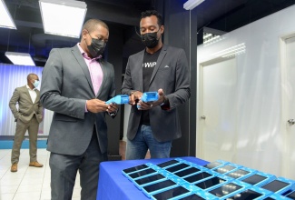 Minister of Agriculture and Fisheries, Hon. Floyd Green (left), speaking with WiPay’s Country Manager for Jamaica, Kibwe McGann, about the point-of-sale terminals that the organisation provides, during the opening ceremony for the entity’s WiPay’s headquarters in New Kingston on August 26.

