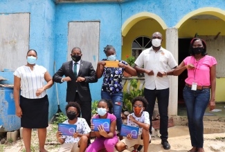 Minister of State in the Ministry of Labour and Social Security, Zavia Mayne (second right, back row), and Minister of Agriculture and Fisheries and Southwest St. Elizabeth member of Parliament, Hon. Floyd Green (second left, back row) with 12-year-old triplets (from left, front row) Dennis, Tamoya, and Denrique Barrett, who recently aced the Primary Exit Profile exams at the Mountainside Primary School in St. Elizabeth. The children display tablets that were presented to them by Mr. Mayne. Sharing the occasion (from left) are Programme of Advancement Through Health and Education (PATH) Social Worker, Lorrie-Ann Love Thompson; the children’s mother, Tamara Barret; and the children’s Grade-six Teacher, Phylicia Ebanks.  