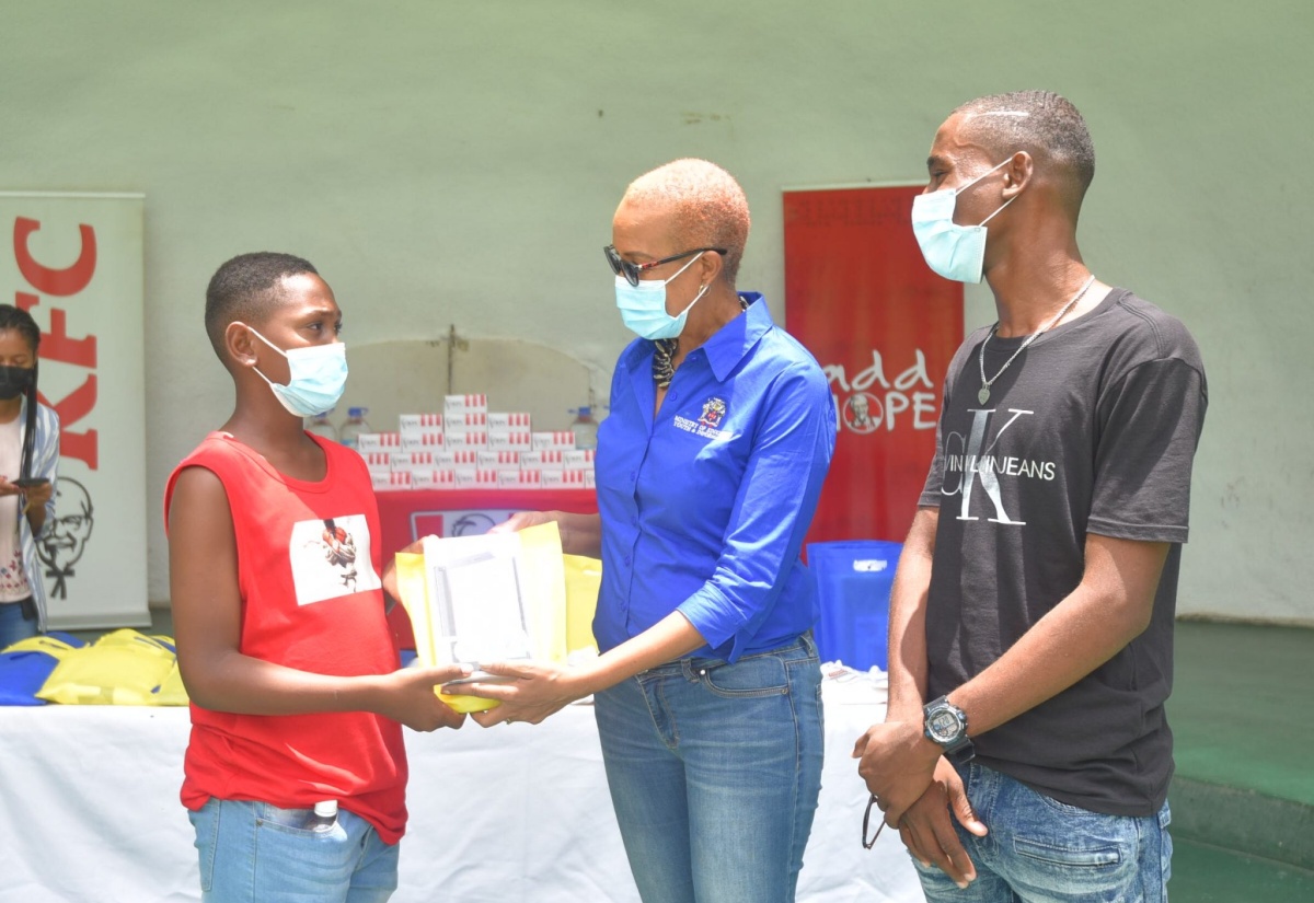 Education, Youth and Information Minister, Hon. Fayval Williams (centre), presents a tablet to Aaron Shields (left) of the Grants Pen Primary and Infant School in St. Thomas, while summer school programme organiser, 16-year old Jaheim Brown, looks on. Occasion was a fun day activity organised by Jaheim at Hope Botanical Gardens in St. Andrew on July 31, to close out the annual summer programme, which he organises for young children in his Yallahs community.