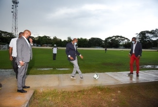 Minister of Tourism, Hon. Edmund Bartlett (centre), kicks a football to Member of Parliament for Western Westmoreland, Morland Wilson (right), at the opening of the new Negril Mini-Stadium on July 30.

