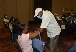 Minister of Tourism, Hon. Edmund Bartlett (right), greeting tourism entrepreneur, Joelle Miller, who is waiting to be vaccinated at the Tourism Vaccination Task Force’s COVID-19 Vaccination Blitz, held at Moon Palace in Ocho Rios, St. Ann, on Friday, September 3. The Minister toured the facilities on the day.  Photo: Okoye Henry

