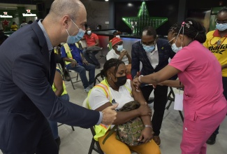 Minister of State for the Ministry of Industry, Investment and Commerce, Hon. Dr. Norman Dunn, (second right), observing Nurse Shannon Bowden (right), as she administers the vaccine to a Red Stripe employee (centre). Red Stripe’s Managing Director, Luis Prata, cheered his employee, as she received her dose. The vaccination was administered at the company’s brewery on Spanish Town Road in Kingston today (September 8). 