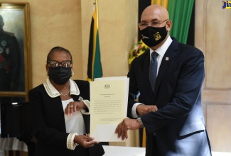 Governor-General, His Excellency the Most Hon. Sir Patrick Allen (right), presents newly appointed Custos Rotulorum for the Parish of St. Catherine, Icylin Golding, with the Instruments of Office during the swearing-in ceremony at King’s House, on Friday (September 24).