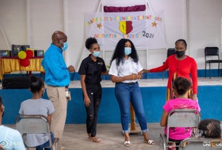 Principal of the Grateful Hill Primary School, George Moodie (left), looks on while teacher at the school, Shanika McCalla Battiste (right), speaks during a recent donation of 40 tablets and bursaries by past student, Unique Gray (second right), at the St. Catherine-based institution. Also pictured at second left is representative of Drive Unique, Adrianna Hunt. 