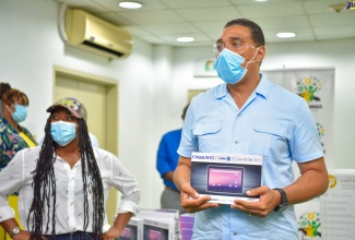 Prime Minister, the Most Hon. Andrew Holness (right), displays one of 60 tablet computers donated to students in Trelawny Northern, at a vaccination blitz held at the Trelawny Multipurpose Stadium, on Thursday (September 23). Sharing in the Moment is Member of Parliament for the constituency, Tova Hamilton (left).