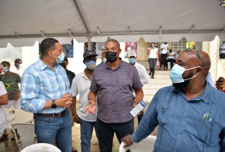 Prime Minister, the Most Hon. Andrew Holness (left), converses with Member of Parliament for North West Manchester, Mikael Phillips, at the Greenvale Community Centre, during a tour of vaccination blitz sites in the parish on Thursday (September 16). In the background (centre) is Minister of Local Government and Rural Development, Hon. Desmond  McKenzie.