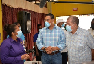 Prime Minister, the Most Hon. Andrew Holness (centre), and Member of Parliament for Manchester North East, Audley Shaw, converse with Dr. Shonette Blair-Walters, during a stop at the vaccination blitz site at Holmwood Technical High School in Manchester on Thursday (September 16).  The Prime Minister visited a number of blitz locations in the parish on the day.