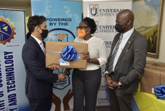 Chairman, Universal Service Fund (USF), Justin Morin (left), presents a laptop to Opposition Spokesperson on Education and Training and Member of Parliament for St. Andrew South West, Dr. Angela Brown Burke, prior to the sitting of the House of Representatives on Tuesday (September 28). Sharing the moment is Chief Executive Officer, USF, Daniel Dawes.

