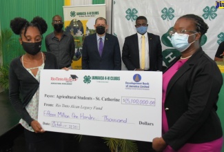 Minister of Industry, Investment and Commerce, Hon. Audley Shaw (centre), who also has responsibility for Agriculture and Fisheries, observes as Rio Tinto Alcan Legacy Fund Scholarship Steering Committee member, Villet Kelly-Bennett (right), presents a symbolic cheque in the sum of $15.1 million to College of Agriculture, Science and Education (CASE) graduate, Quindora Garrett, who accepted on behalf of students and Jamaica 4-H Club members in St. Catherine applying for scholarships to pursue agricultural studies during the 2021/22 academic year. Others (from second left) are Jamaica 4-H Clubs Executive Director, Dr. Ronald Blake; and Rio Tinto Alcan Legacy Fund Scholarship Steering Committee Chairman and Holmwood Technical High School Principal, Hidran McKulsky. The semi-virtual ceremony was hosted by Jamaica 4-H Clubs in Kingston, today (October 21).