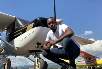 Aspiring pilot Rohan Ellis stoops in front of the Cessna aircraft on which he is learning to fly at the Aeronautical School of the West Indies (ASWI), which is located at the Tinson Pen Aerodrome, Kingston. 