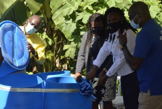 Operations Director at the National Solid Waste Management Authority (NSWMA), Aretha McFarlane (second right), cuts the ribbon to mark the official handing over of plastic disposal bins to the community of Chambers Pen, Hanover, during the launch of a solid waste reduction programme in the area on Thursday (November 4). Participating in the handing over (from left) are: Executive Director of the NSWMA, Audley Gordon; Member of Parliament for Western Hanover, Tamika Davis; and Regional Operations Manager at the Western Parks and Market (WPM) Waste Management Limited, Garnet Edmondson.