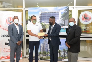 Minister of Health and Wellness, Dr. the Hon. Christopher Tufton (2nd left), hands over a cheque valued at $144 million to Chief Executive Officer of the University Hospital of the West Indies (UHWI), Kevin Allen (2nd right) for the construction of a new building under the hospital’s redevelopment project. The presentation took place at the facility in St. Andrew on Friday (December 17). Sharing in the occasion (from left) are: Medical Chief of Staff at UHWI, Dr. Carl Bruce, and Senior Director at the hospital, Fitzgerald Mitchell.