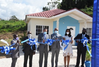 Prime Minister, the Most Hon. Andrew Holness (third left), cuts the ribbon to open Perth Estate Phase 1A in Mandeville, Manchester following the handing over of keys to beneficiaries on December 15.  Joining him (from left) are: Citizens Association representative - Horace Haighs; Minister of Housing, Urban Renewal, Environment and Climate Change, the Hon. Pearnel Charles Jr.; NHT Chairman, Lennox Channer; Member of Parliament for Manchester Central, Rhoda Crawford; and Managing Director of NHT, Martin Miller.