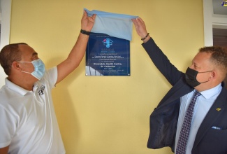 Minister of Health and Wellness, Dr. the Hon. Christopher Tufton (left), and Jamaica’s Consul General to Miami, Florida Oliver Mair, unveil a plaque at a ceremony for the adoption of the Riversdale Health Centre, in St. Catherine, on January 19.