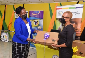 Minister of Education and Youth, Hon. Fayval Williams (right), receiving one of 500 laptops that were donated by the Transformational Implementation Unit (TIU) to the Child Protection and Family Services Agency (CPFSA). The handover ceremony was held at the CPFSA headquarters in Kingston on Wednesday (January 19).    