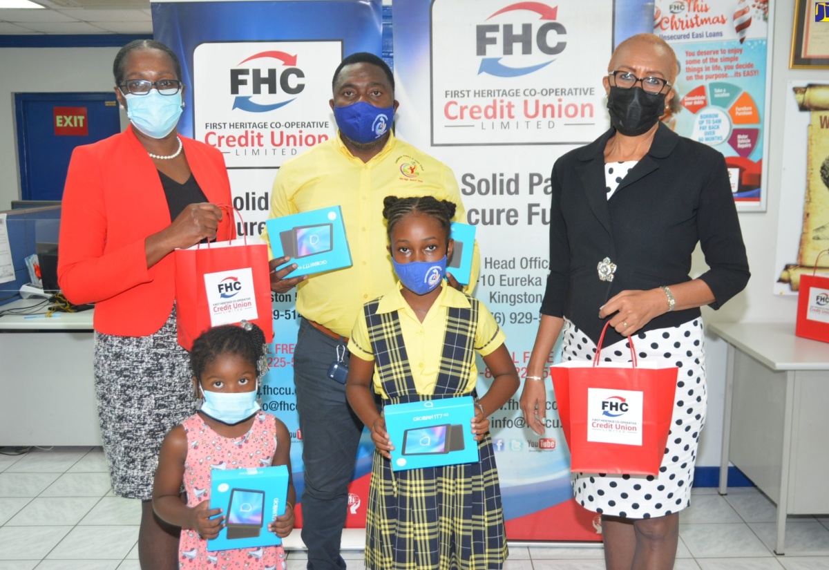 Minister of Education and Youth, Hon. Fayval Williams (right), participates in the handover of tablets to students of Chatsworth Primary and Infant School in Maroon Town, St. James, by First Heritage Co-operative (FHC) Credit Union, at the entity’s Montego Bay Branch office on Thursday, January 27. Joining the Minister is FHC Branch Manager, Marcia Bailey (back row, left); Chatsworth Primary’s Principal, Lesga Miller (centre); and students Camoyah Gordon (front row, left); and Dejanae Cole. 