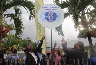 Chief Executive Officer of the Universal Service Fund (USF), Daniel Dawes (third left); Custos of Manchester, Hon. Garfield Green (fourth left); Member of Parliament for Manchester North West, Mikael Phillips (right), and community members celebrate the recent launch of the free secured Wi-Fi hotspot, in Mile Gully, Manchester.

