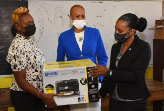 Member of Parliament for St. Andrew West Rural, the Hon. Juliet Cuthbert Flynn (left), and Minister of Education, Youth and Information, the Hon. Fayval Williams (centre), hands over a cartridge-free Epson printer to the Acting Principal of Rock Hall Primary School, Keisha Mehabear, during a visit to the school in rural St. Andrew on Tuesday (January 4). The printer, along with printing paper, was donated by the Usain Bolt Foundation. 