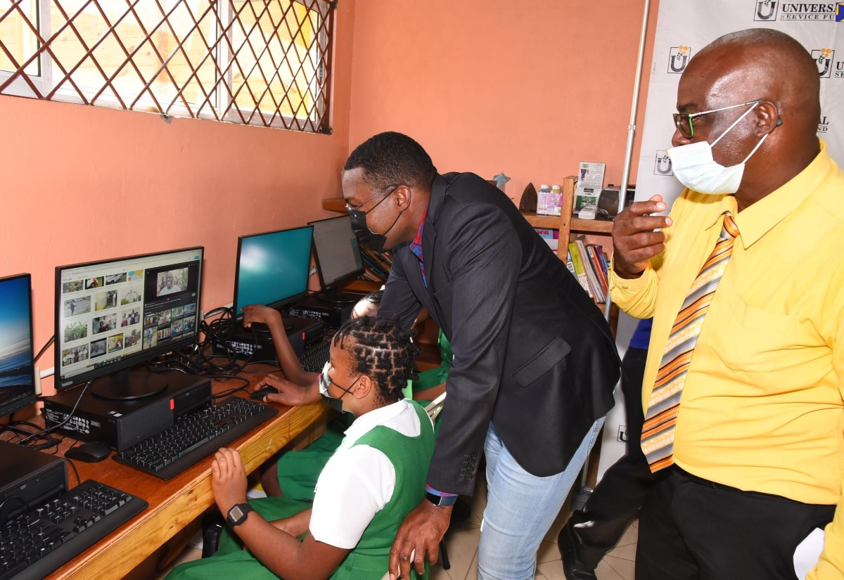 Minister of Information and Member of Parliament for Clarendon North Central, the Hon. Robert Morgan (centre), assists Grade six student, Anecia Simpson, in using a computer at the new Community Access Point (CAP) site, which opened at the Brixton Hill Primary and Infant School in the parish on Wednesday (January 19). Looking on, is Principal of the school, Leon Clare. The facility, established by the Universal Service Fund (USF), is equipped with 20 computers, a projector with accompanying screen and mount, and desks and chairs. It will provide residents, especially students, with access to Wi-Fi services to participate in online learning.