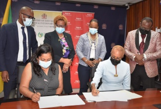 Minister of Education and Youth, Hon. Fayval Williams (seated right) and Chief Executive Officer of the Digicel Foundation, Charmaine Daniels (seated left), sign the agreement for the establishment of a Smart Computer Lab at the Harry Watch Primary School in Manchester. Observing (from left, standing) are Principal of the school, Fitzroy Francis; Acting Permanent Secretary in the Ministry, Maureen Dwyer; Acting Chief Education Officer, Dr. Kasan Troupe; and Regional Director for Region 5, Ottis Brown. The signing ceremony was held at the Ministry in Kingston on Wednesday (February 2). 