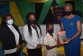 Minister of Education and Youth, Hon. Fayval Williams (right) presents student of Excelsior Primary and Infant School, Kingston, Devaunte Baccas with a tablet during the handover of the devices by the Optimist Club of Kingston on February 3. Sharing in the moment are (from left): patron of Optimist Club of Kingston, Wife of the Governor- General, Her Excellency the Most Hon. Lady Allen; and President of the Optimist Club of Kingston, Aneskia Smalling. The activity is one of several to commemorate International Optimist Day which is celebrated on the first Thursday in February of each year.