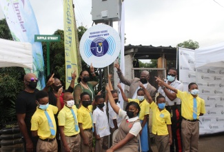 Member of Parliament for St. Andrew East Rural, the Most Hon. Juliet Holness (third left, back row), joins Chief Executive Officer of the Universal Service Fund (USF), Daniel Dawes (second right, back row); teacher at the Woodford Primary School, Christine Tapper (second left, back row); students and community stakeholders, at the recent launch of the Woodford Wi-Fi hotspot in the constituency.

