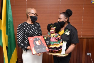 Minister of Education and Youth, Hon. Fayval Williams (left), is presented with a book authored by Pat Chin, entitled ‘Miss Pat – My Reggae Music Journey’, and a doll dressed in the Jamaican colours by proprietor of Island Dolls, Beverly Robotham.  The representation was made at the Ministry in Kingston on Tuesday (February 22).  Ms. Robotham also presented a letter of undertaking to donate five per cent of all doll sales for this year towards the purchase of tablets for students, under the ‘Own Your Own Device’ initiative. 
 
