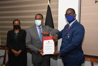 Minister of Finance and the Public Service, Dr. the Hon. Nigel Clarke (centre) and Jamaica Teachers’ Association (JTA) President, Winston Smith, display the signed Heads of Agreement for wage increases for teachers, during a brief ceremony at the Ministry in Kingston on Monday (February 21). At left is State Minister, Hon. Marsha Smith.