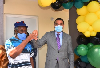 Prime Minister, the Most Hon. Andrew Holness (right), hands over the keys to a three-bedroom house to Henry Dwyer at Donmair Close in  St. Andrew North Central, on February 16. The unit was built under the New Social Housing Programme. 
 
