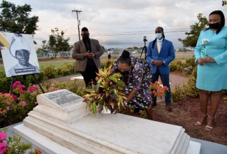 Culture, Gender, Entertainment and Sport Minister, Hon. Olivia Grange (second left), places a potted plant on the grave of  the late Jamaican artist and religious leader, Mallica “Kapo” Reynolds, to commemorate the anniversary of his birth on February 10, 1911. He died February 24, 1989. The ceremony was held at the National Heroes Park on February 10.  Looking on are (from left) Director of Events Management Production, Jamaica Cultural Development Commission (JCDC), Gregory Simms; State Minister in the Ministry, Hon. Alando Terrelonge; and Acting Executive Director,  JCDC, Lillian Reid. One of his paintings, ‘Shining Spring’, was selected by the Jamaican Government as a wedding gift for the 1981 wedding of Prince Charles and Lady Diana (now deceased). 