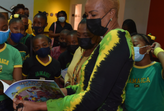 Minister of Education and Youth, Hon. Fayval Williams (right), and Minister of Culture, Gender, Entertainment and Sport, Hon Olivia Grange (second right), look through a Jamaican colouring book with primary-school students, during a visit to the National Gallery of Jamaica, downtown Kingston, on Jamaica Day (February 25).