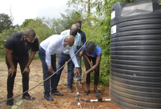 Tourism Minister, Hon. Edmund Bartlett (second left), interacts with farmer from Short Hill, St. Elizabeth, Nicolea Scott (right), as she explains the mechanics of the irrigation system on her farm. Looking on (from left) are: Minister without Portfolio in the Office of the Prime Minister, Hon. Floyd Green; Minister of State in the Ministry of Agriculture and Fisheries, Hon. Frank Witter (third from left); and Executive Director of the Tourism Enhancement Fund, Dr. Carey Wallace.

