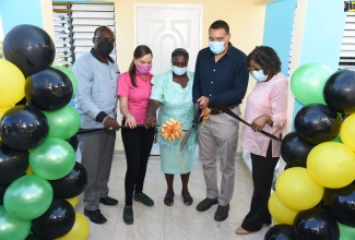 Prime Minister, the Most Hon. Andrew Holness (second right), cuts the ribbon at the handover of a three-bedroom unit in Shot Over, Port Antonio, Portland, recently. Sharing the moment (from left) are Mayor of Port Antonio, Paul Thompson; Member of Parliament for Portland East, Ann-Marie Vaz; mother of the beneficiary, Brenda Thompson, and Permanent Secretary at the Office of the Prime Minister (OPM), Audrey Sewell.