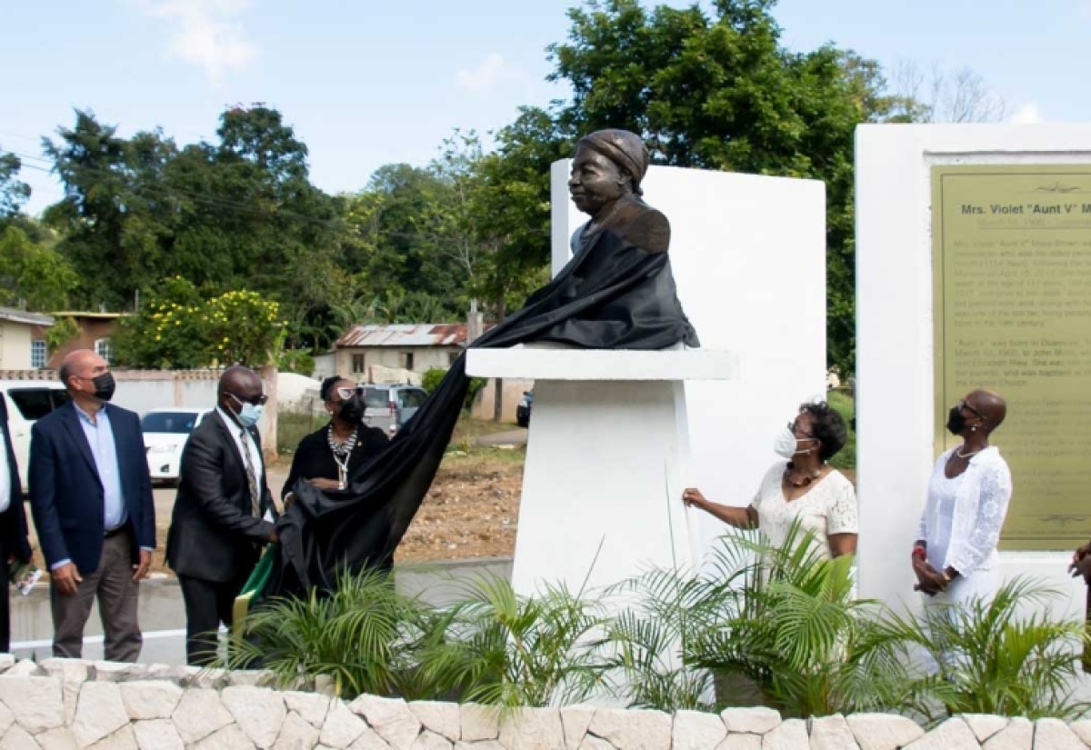 Minister of Culture, Gender, Entertainment and Sport, Hon. Olivia Grange (fourth left), is assisted by Chairman of the Trelawny Municipal Corporation and Mayor of Falmouth, Councillor Colin Gager, in unveiling the monument in honour of supercentenarian Violet Mosse Brown in Duanvale, Trelawny, on March 10. Sharing the moment are (L-R) Councillor for the Sherwood Content Division, Dunstan Harper; Custos of Trelawny, Hugh Gentles; Sculptor, Pamrie Hall Dwyer; and granddaughters of Mrs. Mosse Brown, Dr. Beverly Davis Fray and Lelieth Palmer.  