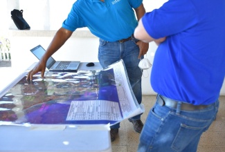 Min. Samuda looks at map showing Mangrove areas in Clarendon while being briefed by Professor Terrence Forrester, Chief Scientist & Managing Director, UWI Solutions for Developing Countries (SODECO).