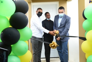 Prime Minister, the Most Hon. Andrew Holness (right), and Member of Parliament for Hanover Eastern, Dave Hume Brown (left), join New Social Housing Programme (NSHP) beneficiary, Michelle Campbell (centre), in cutting the ribbon to her new three-bedroom housing unit in Bessie Baker, Mount Peto, Hanover on Thursday, April 7.  
 
