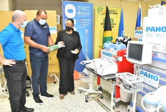 Minister of Health and Wellness, Dr. the Hon Christopher Tufton (centre), is shown new medical equipment donated by the Pan American Health Organization (PAHO) to strengthen Jamaica’s COVID-19 response, by Advisor for Health Emergencies at PAHO country office in Jamaica, Dr. Marion Bullock DuCasse (right). Looking on is PAHO/WHO representative to Jamaica, Bermuda and the Cayman Islands, Ian Stein, who made the presentation at PAHO’s country office in Kingston on April 20.  